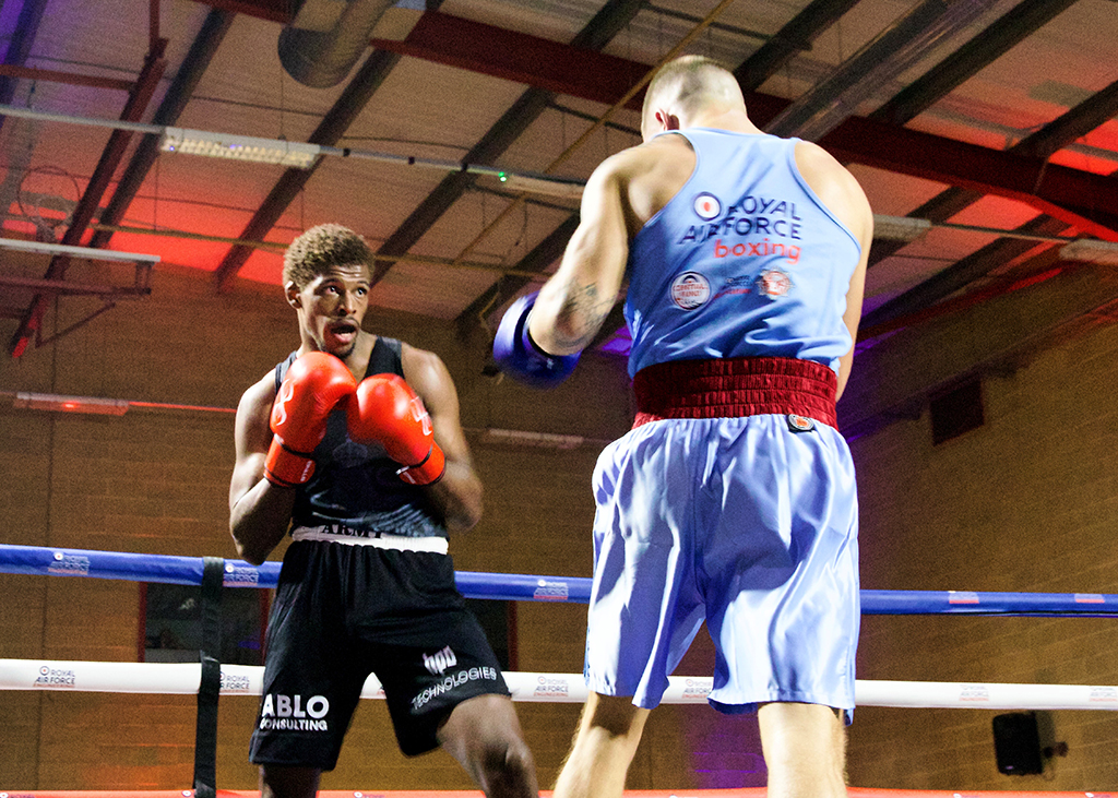 A British Army boxer focuses on his RAF opponent during a match inside a boxing ring.
